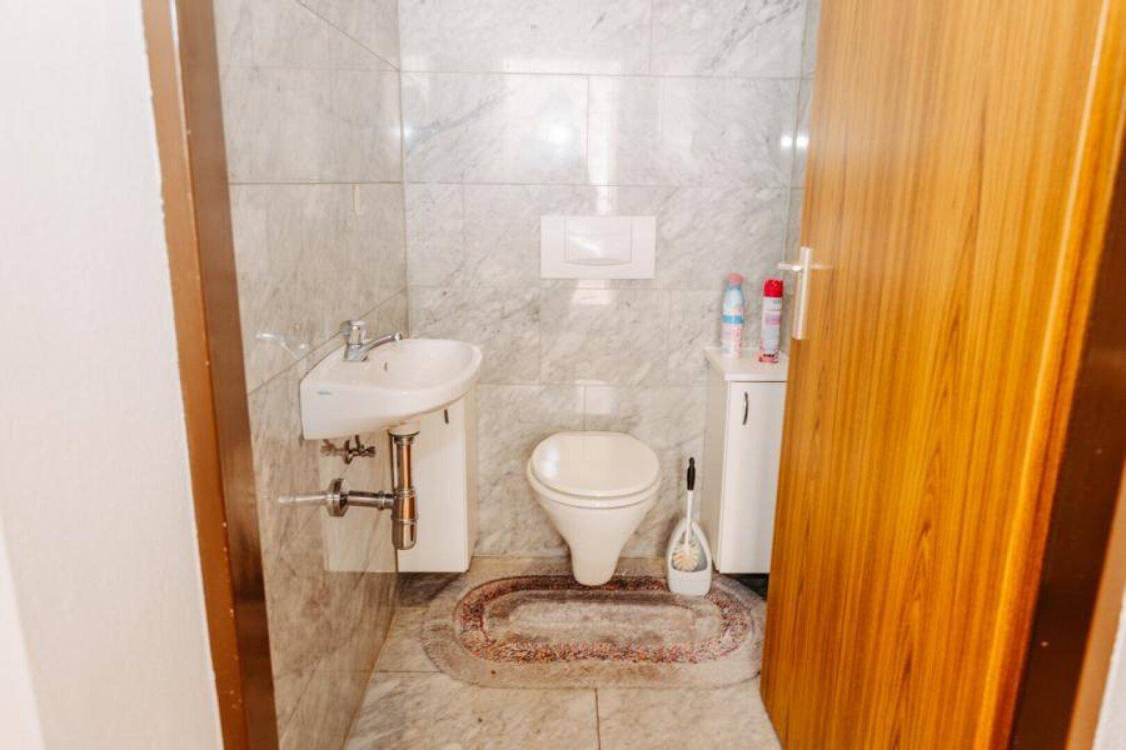 Kleines Gäste-WC mit hellen Marmorfliesen, wandhängendem WC und kleinem Waschbecken.