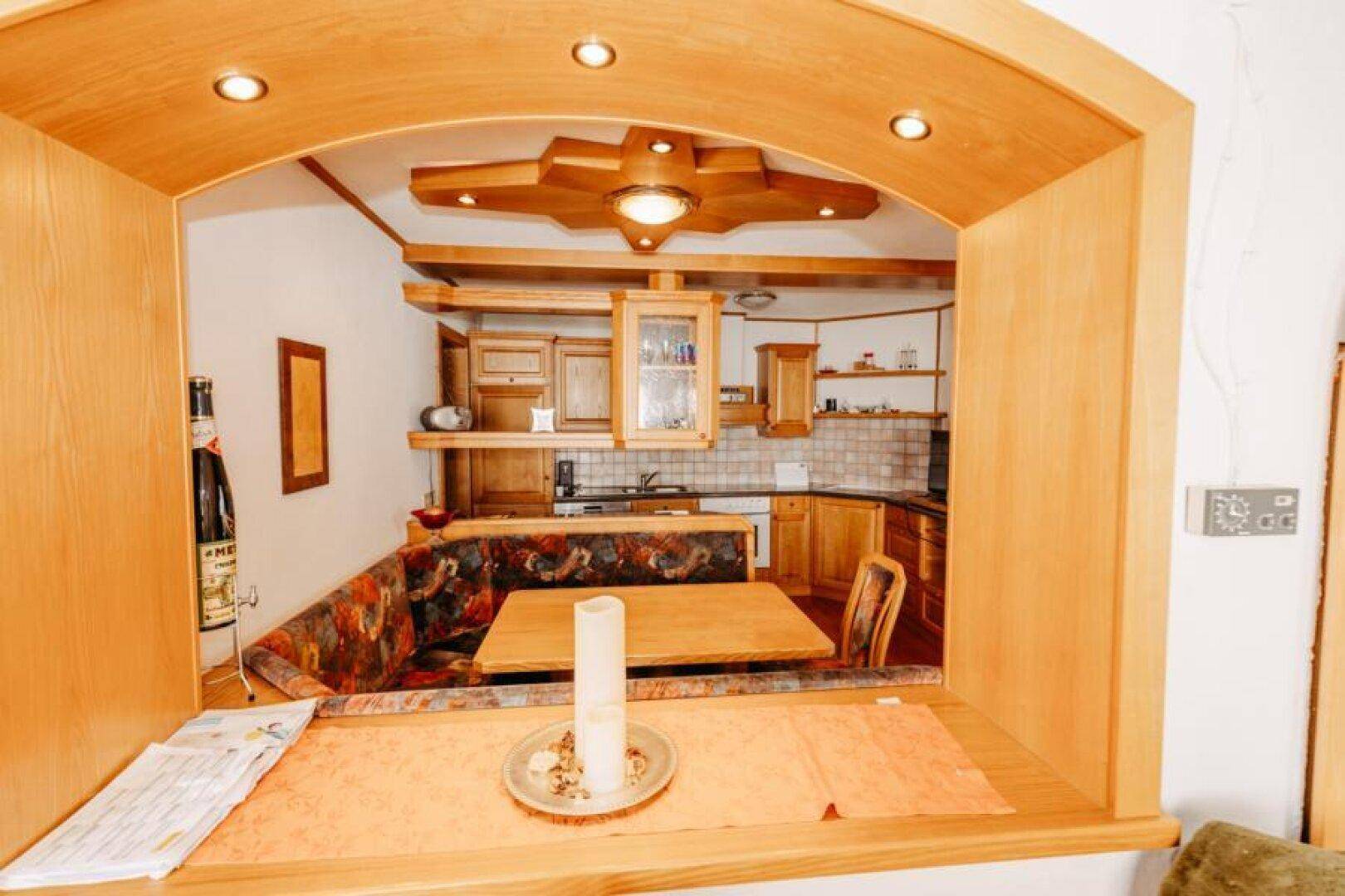 Blick durch einen Bogen in eine traditionelle Holzküche mit gemütlicher Essecke.