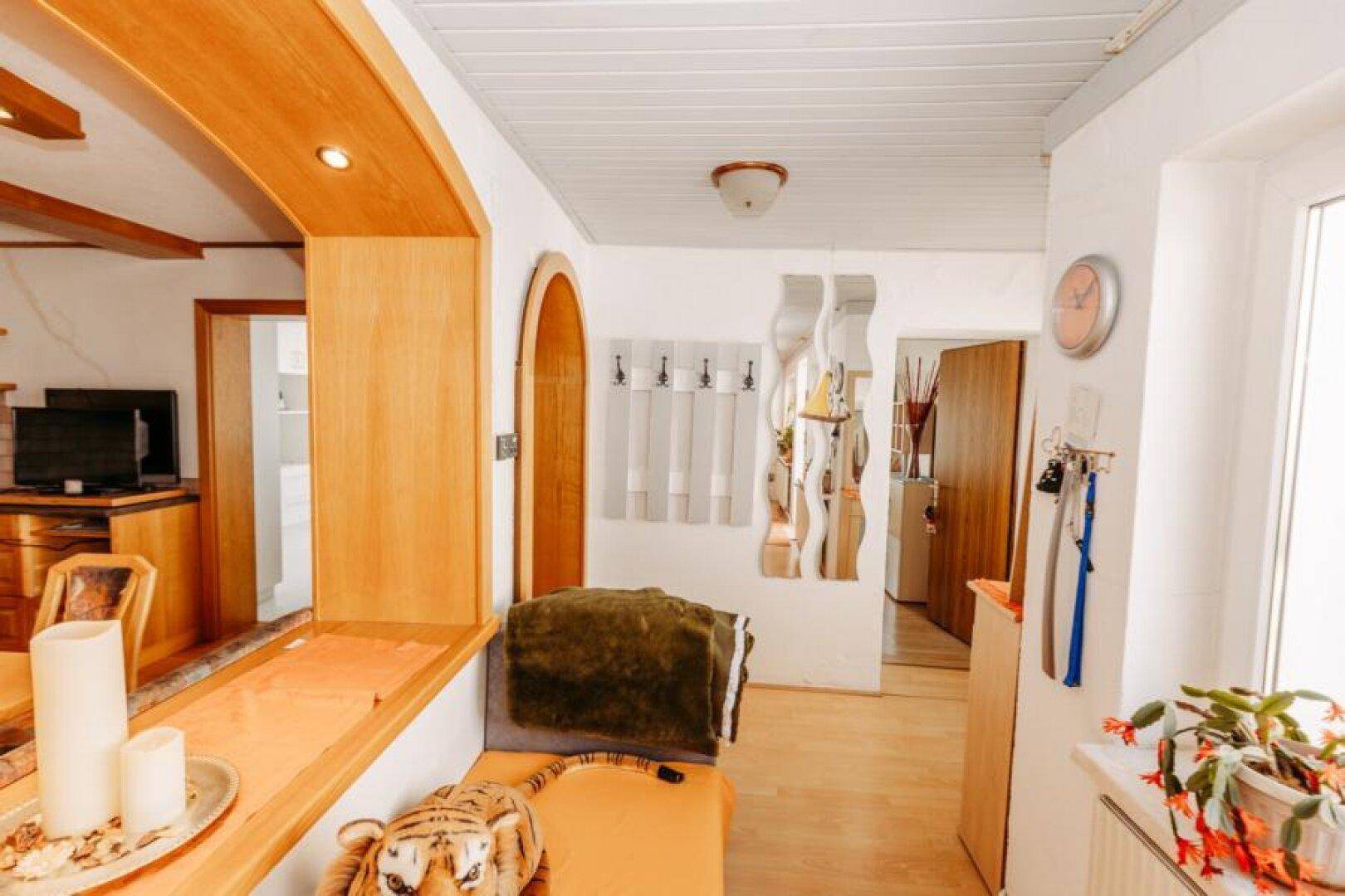 Heller Flur mit Holzfußboden und dekorativen Spiegeln, der zu den angrenzenden Räumen führt.