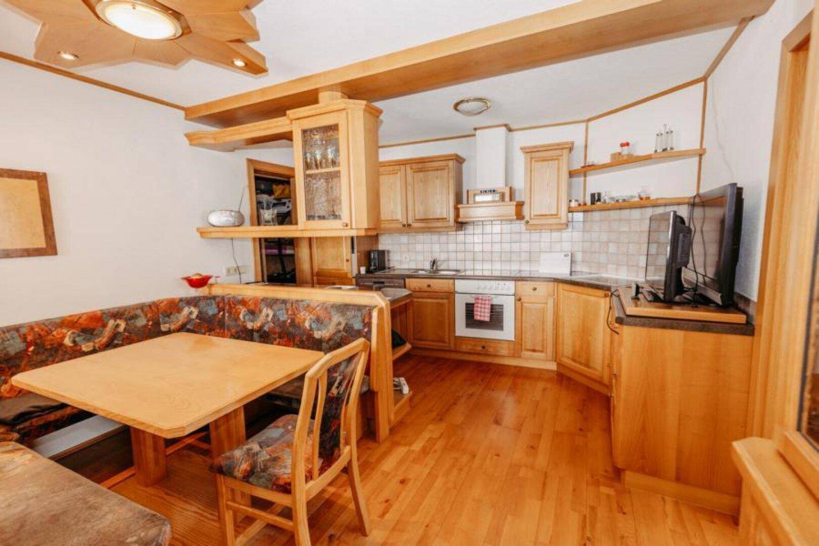 Gemütliche Holzküche mit Essecke, Einbauschränken und integriertem Backofen.