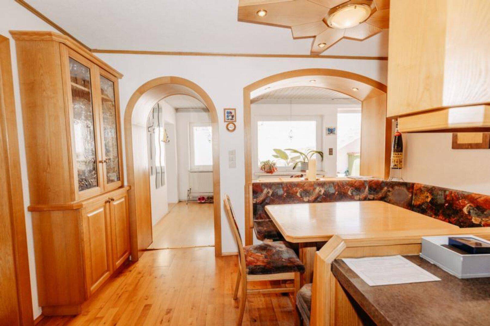 Blick von der Küche in den Flur mit Holzelementen und Rundbögen.