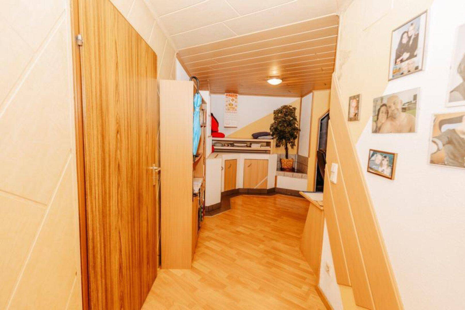 Eingangsbereich mit Holzfußboden, Treppe und persönlichen Familienfotos an der Wand.