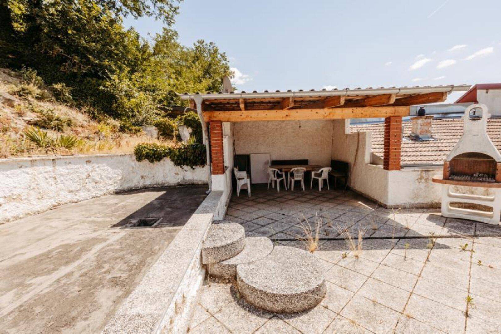 Geräumige Terrasse mit überdachtem Sitzbereich und gemauertem Grill für gesellige Abende.