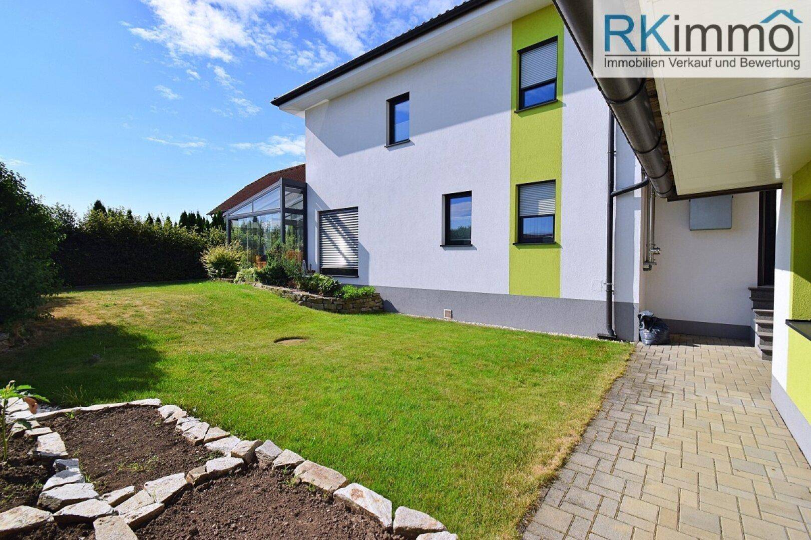 Gepflegter Gartenbereich neben dem Haus mit Rasenfläche und einem kleinen Hochbeet für Pflanzen.