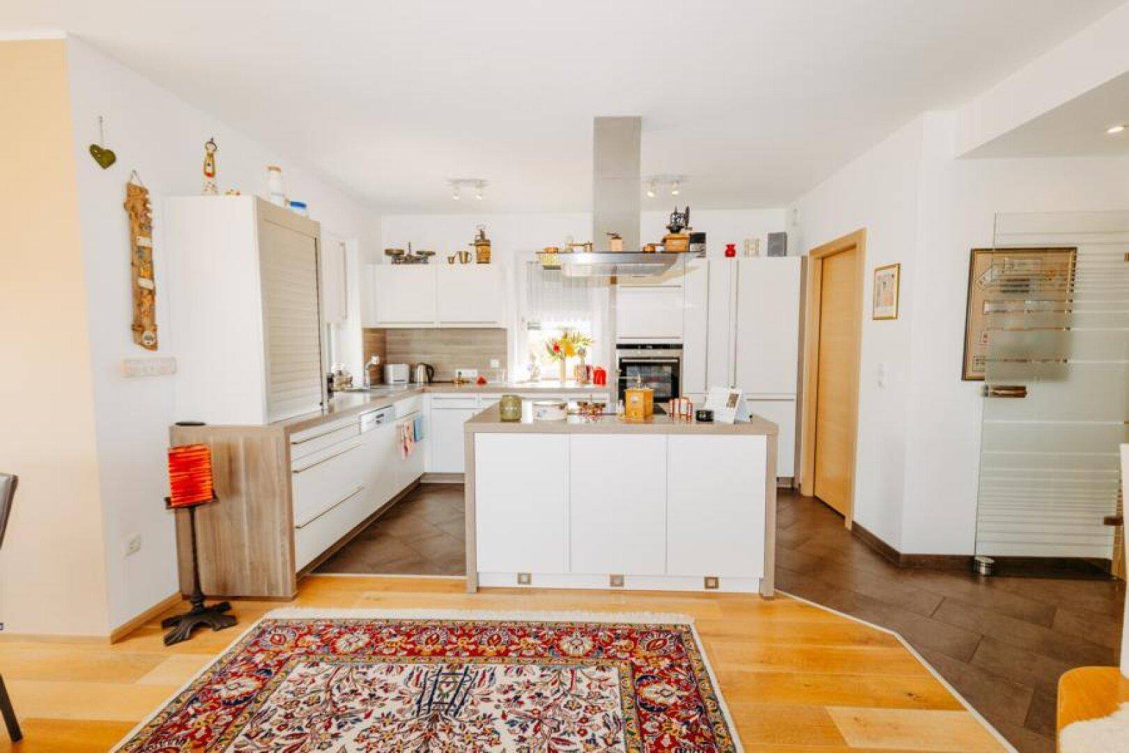 Moderne offene Küche mit weißer Kücheninsel, Holzarbeitsplatten und integrierten Geräten.