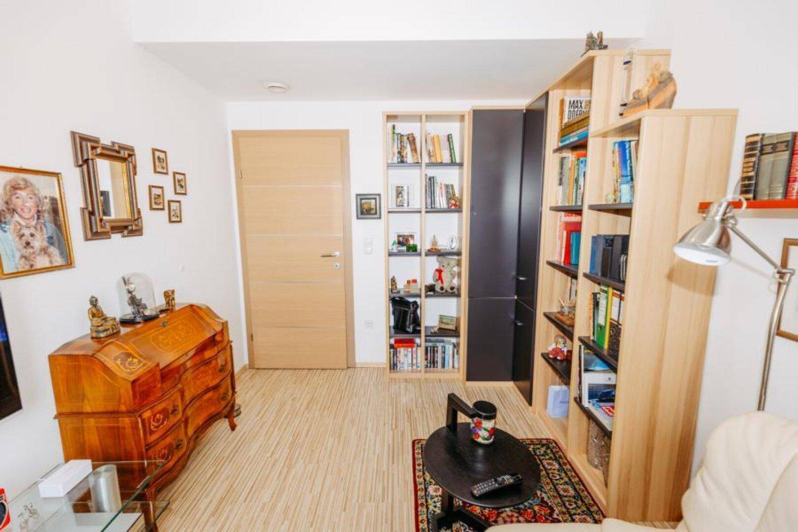 Arbeitszimmer mit Holzboden, Bücherregalen und einem antiken Schreibtisch, gut beleuchtet.