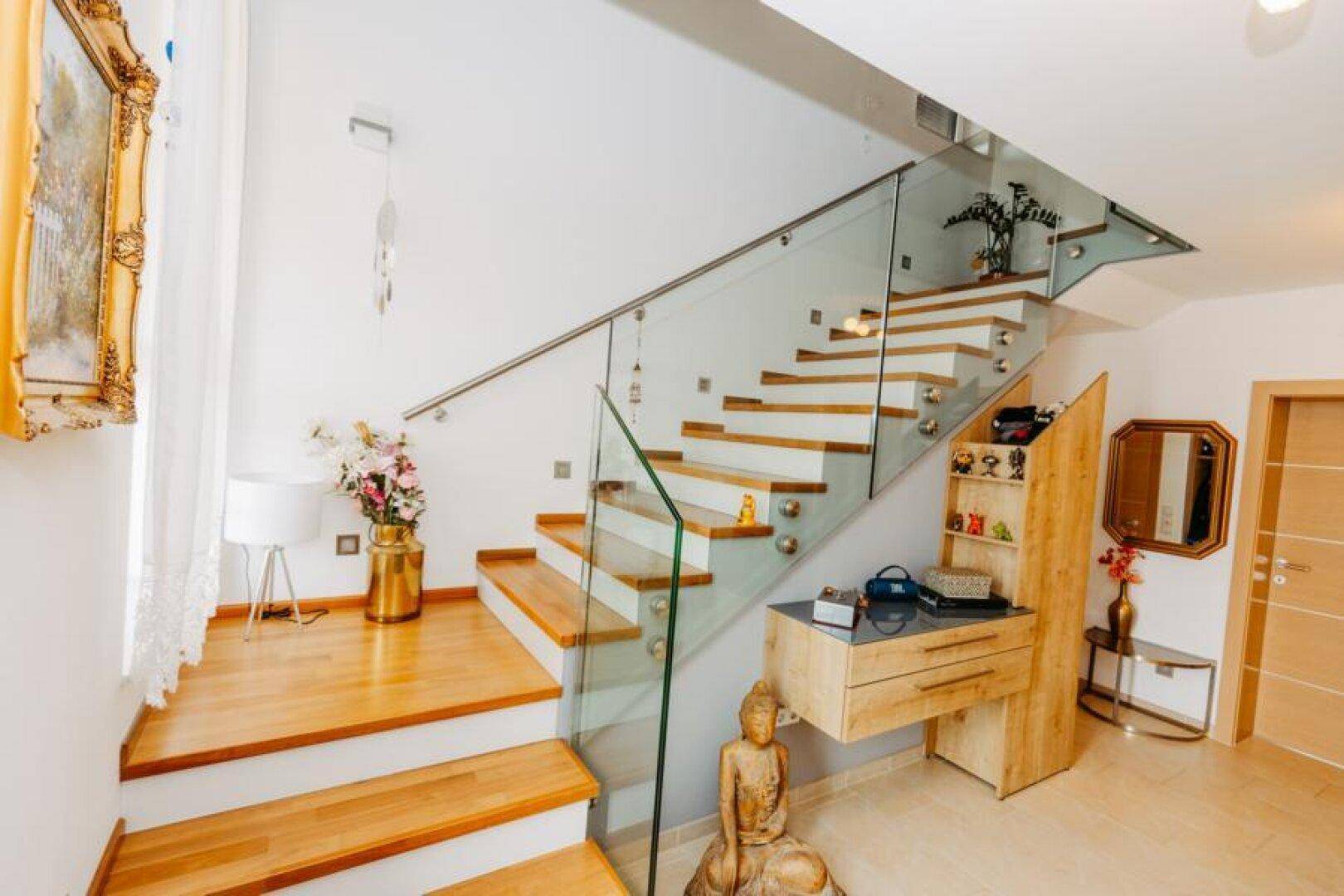 Elegante Holztreppe mit Glasgeländer und modernen Dekorationselementen, hell und offen.