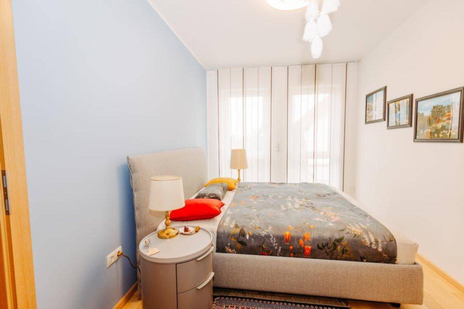 Helles Schlafzimmer mit Doppelbett, blauer Akzentwand und modernen Nachttischen.