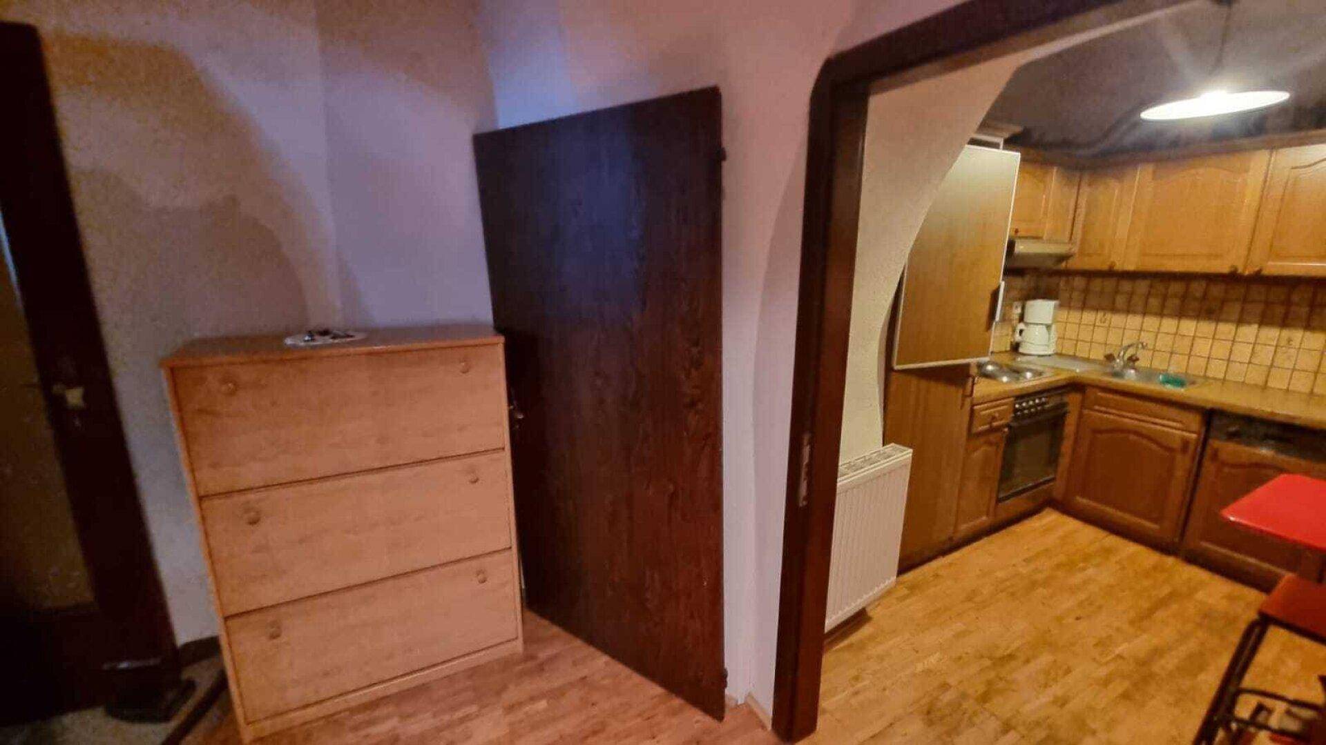 Kleine Küche mit Holzschränken, Herd und Spüle, integriert in einen Nischenbereich.