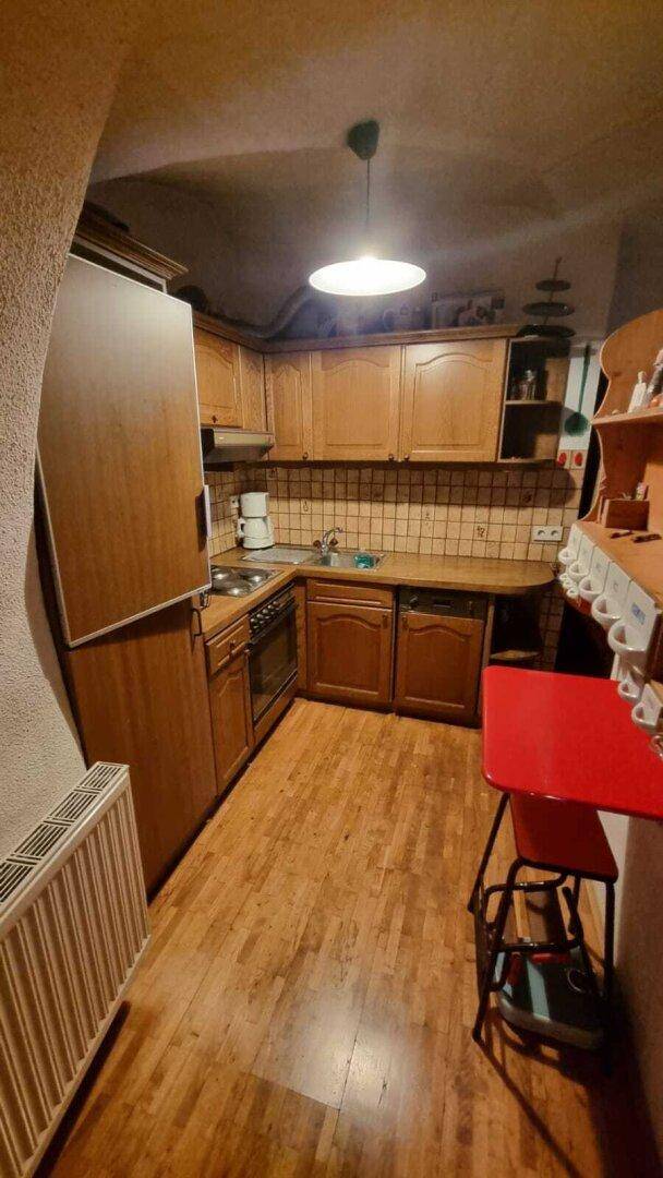 Funktionale Küche mit Holzschränken, integriertem Kühlschrank und einem kleinen Essbereich.