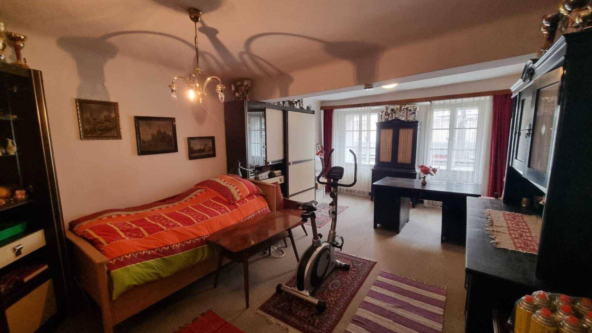 Geräumiges Zimmer mit Bett, Schreibtisch und einem Heimtrainer, genutzt als Schlaf- und Arbeitsbereich.