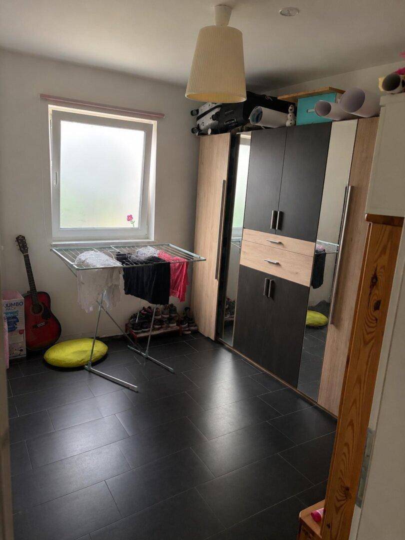 Praktischer Raum mit Kleiderschrank, Wäscheständer und dunklem Fliesenboden.