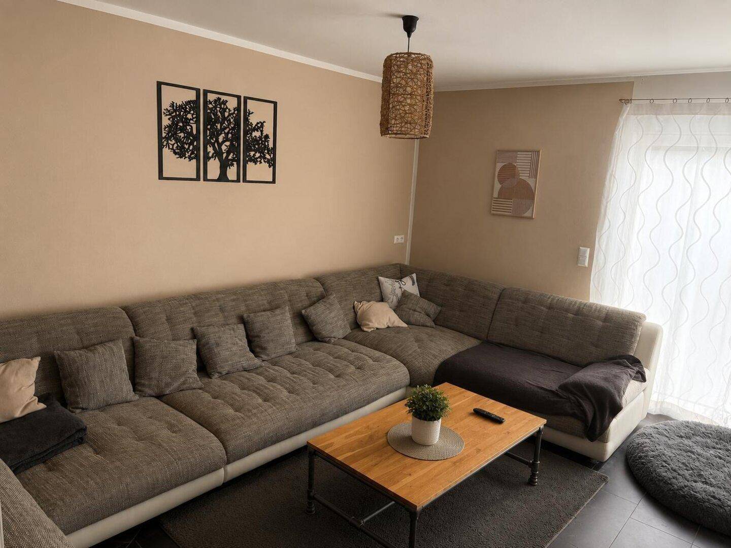 Gemütliches Wohnzimmer mit großem Ecksofa, Couchtisch und beigefarbenen Wänden.