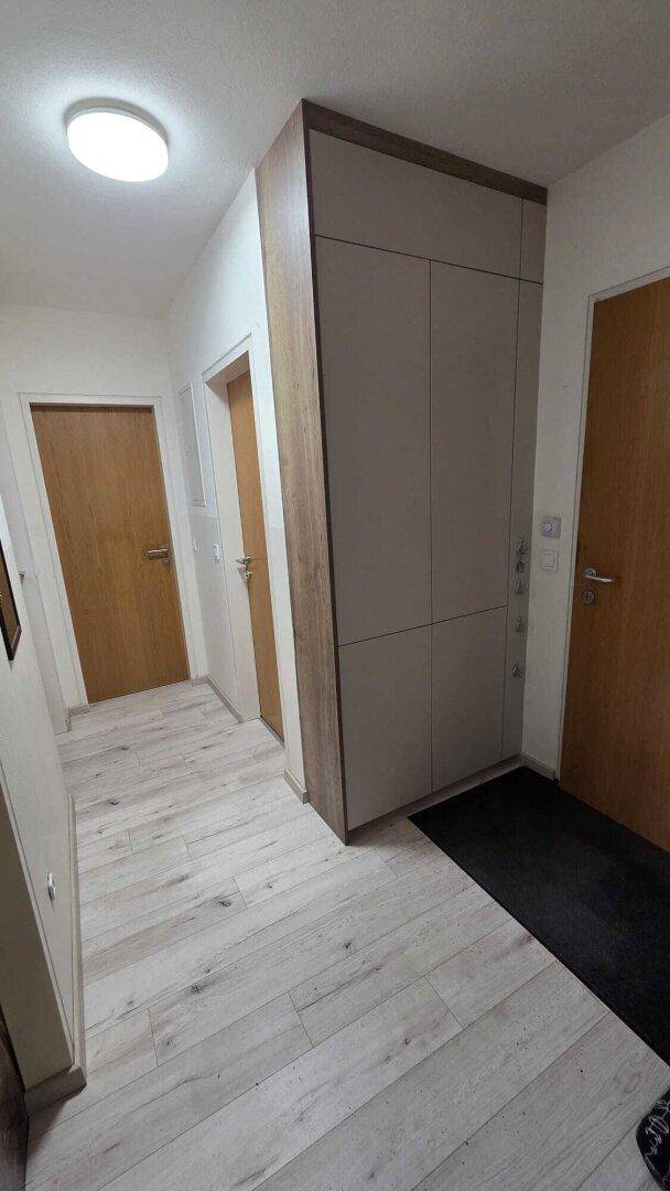 Heller Flur mit modernem Laminatboden und praktischen Einbauschränken für zusätzlichen Stauraum.