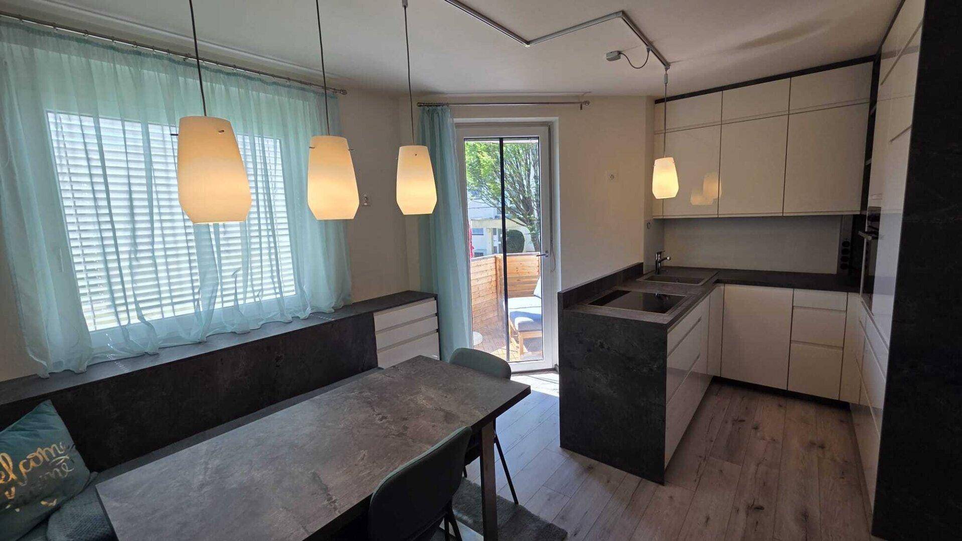 Helle Küche mit Essbereich, modernen Schränken und direktem Zugang zum Balkon.