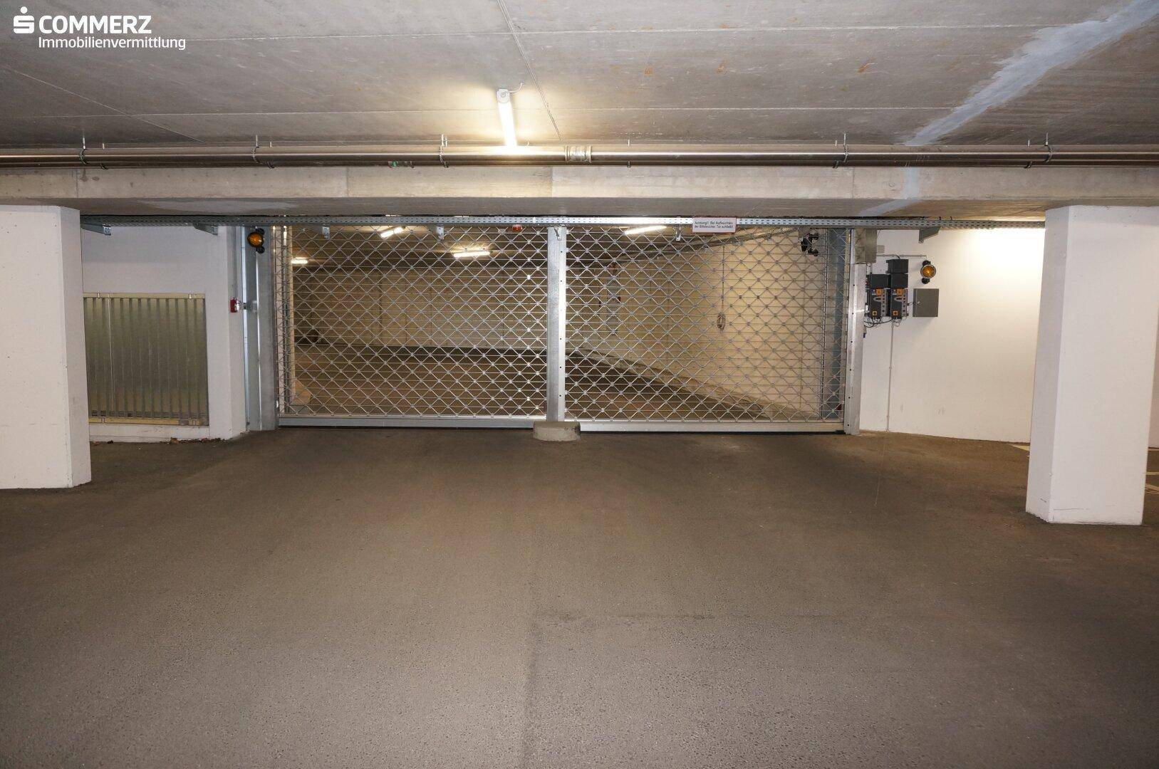 Innenansicht einer Tiefgarage mit einem Metallrolltor und Beleuchtung.