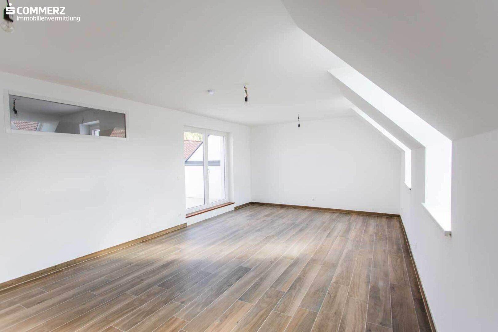Heller Dachbodenraum mit Laminatboden und Zugang zu einem Balkon oder einer Dachterrasse.