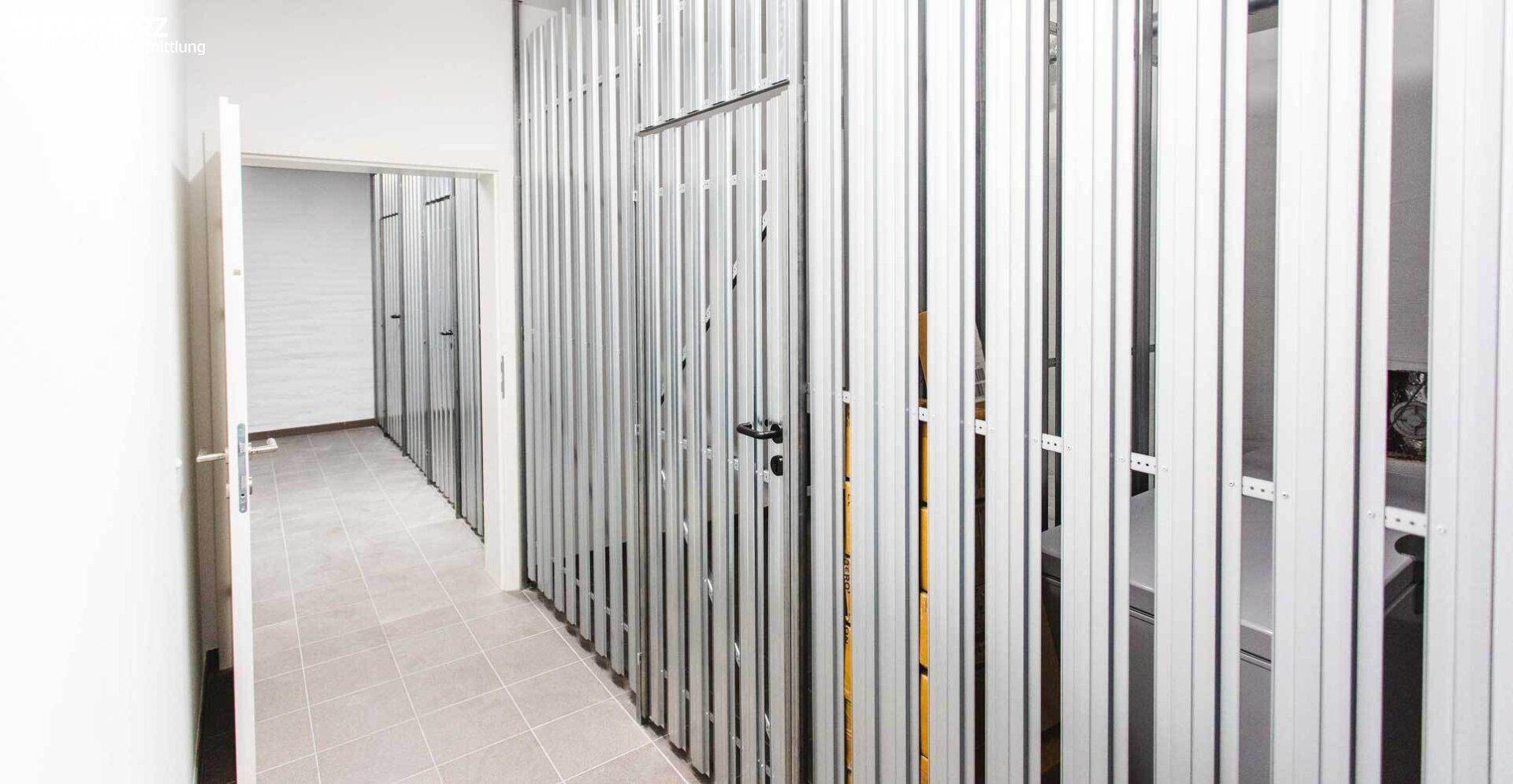 Geräumiger Abstellraum mit Metallabtrennungen und Fliesenboden, ideal für zusätzlichen Stauraum.