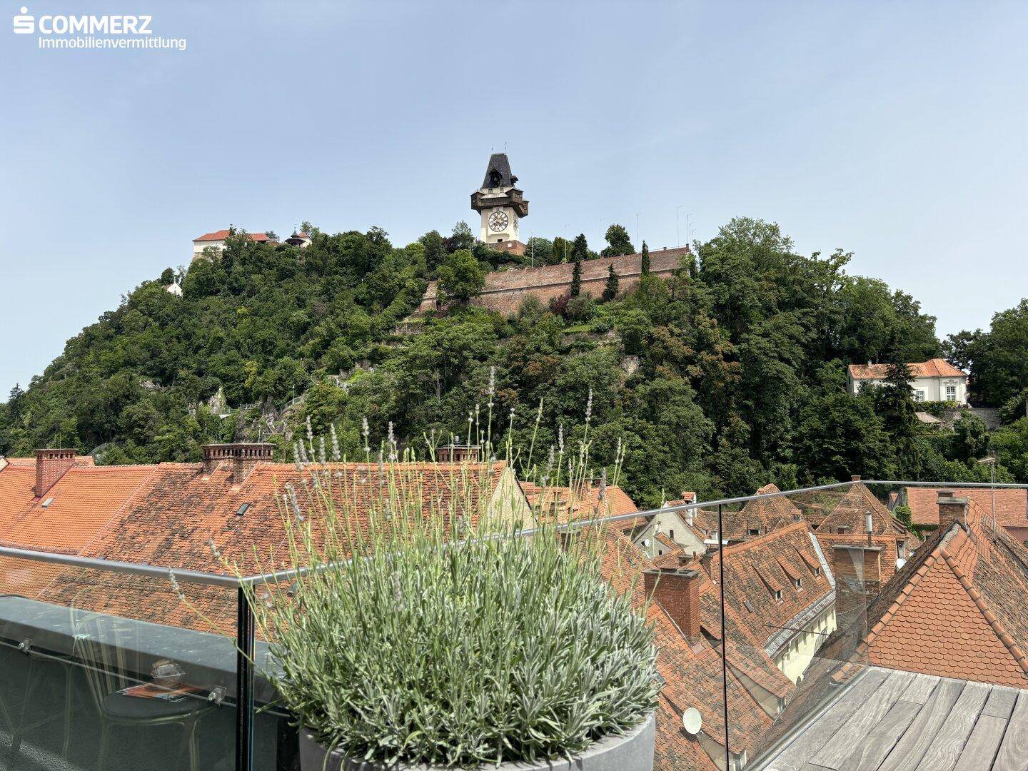 Blick von einer Dachterrasse über die Dächer der Stadt zum Grazer Uhrturm auf dem Schlossberg.