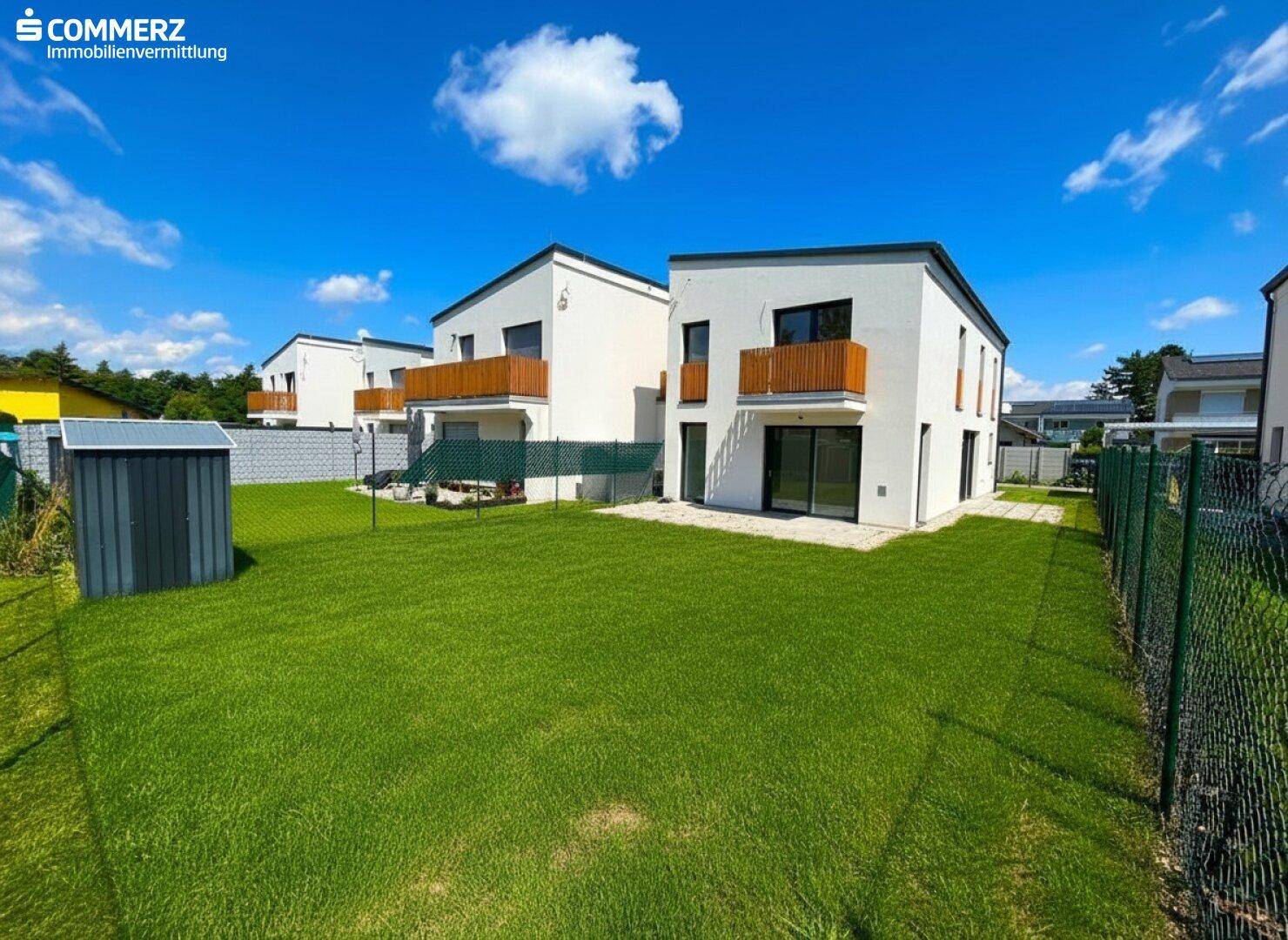 Reihe von modernen Häusern mit gepflegten Gärten, Balkonen und einem Gartenschuppen.
