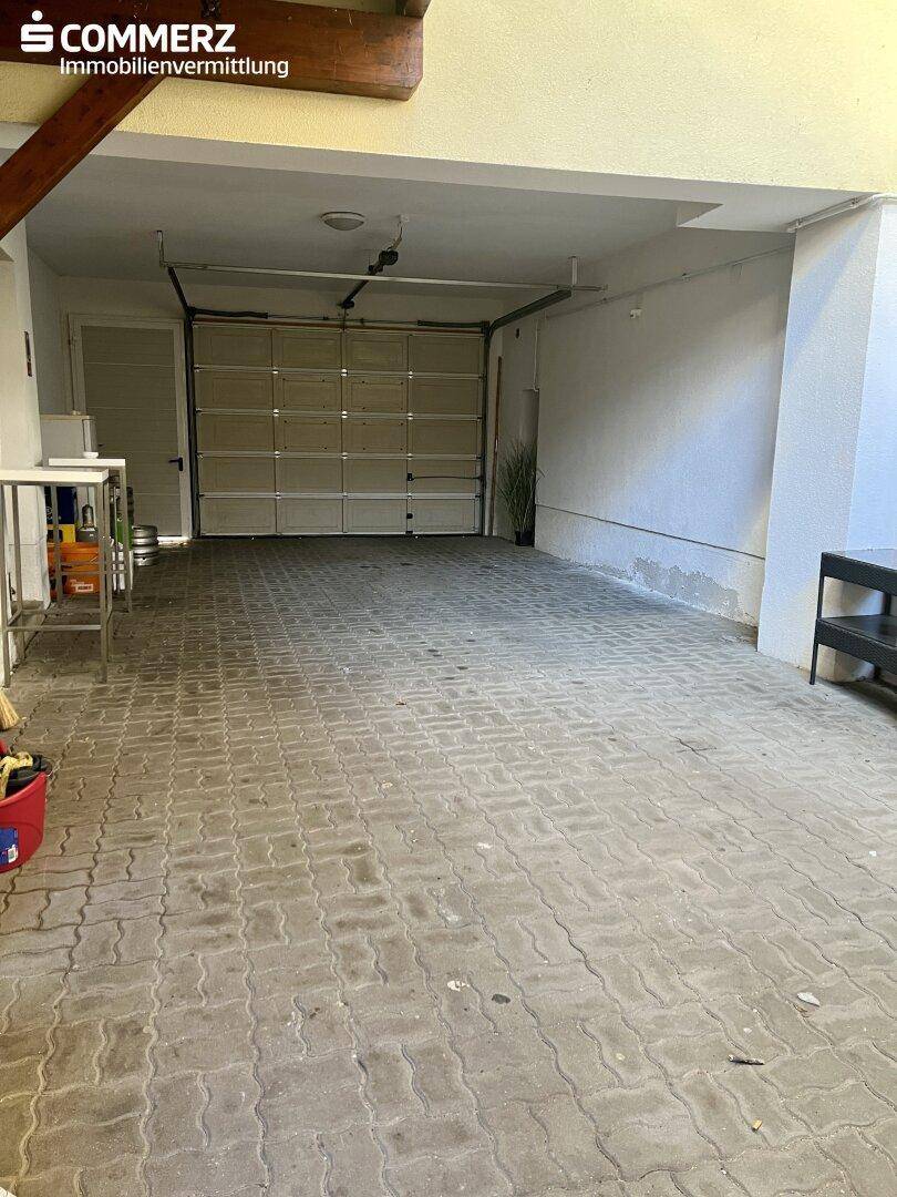 Geräumige Garage mit Betonpflasterboden und großem Garagentor, bereit zur individuellen Nutzung.