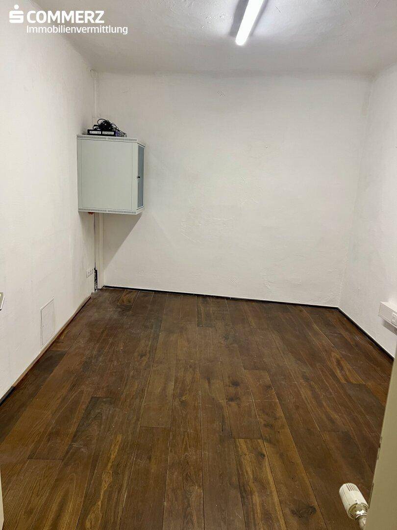 Kleiner Abstellraum mit dunklem Holzboden, weißen Wänden und einem praktischen Wandschrank.