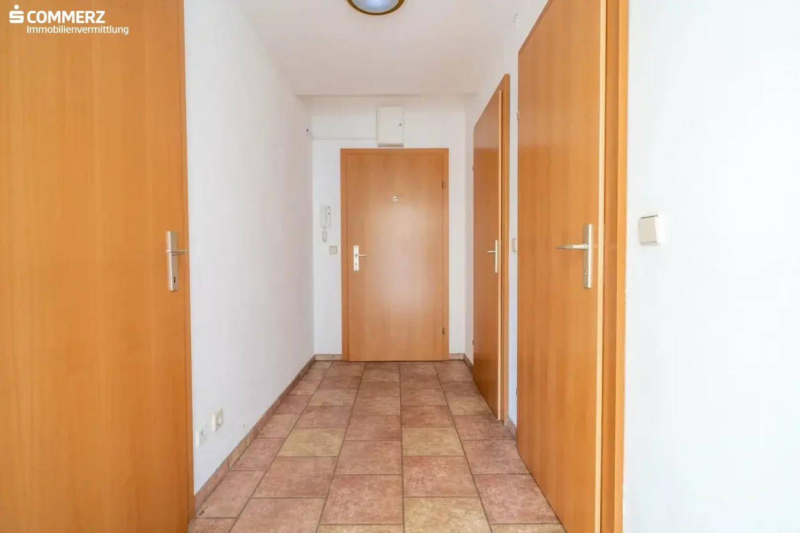 Eingangsbereich des Flurs mit Fliesenboden und mehreren Türen, inklusive Gegensprechanlage.