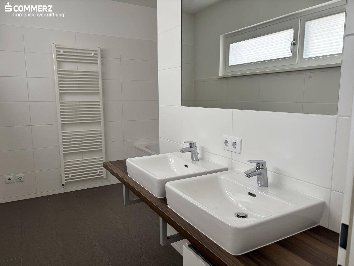 Modernes Badezimmer mit Doppelwaschbecken, großem Spiegel und beheiztem Handtuchhalter.