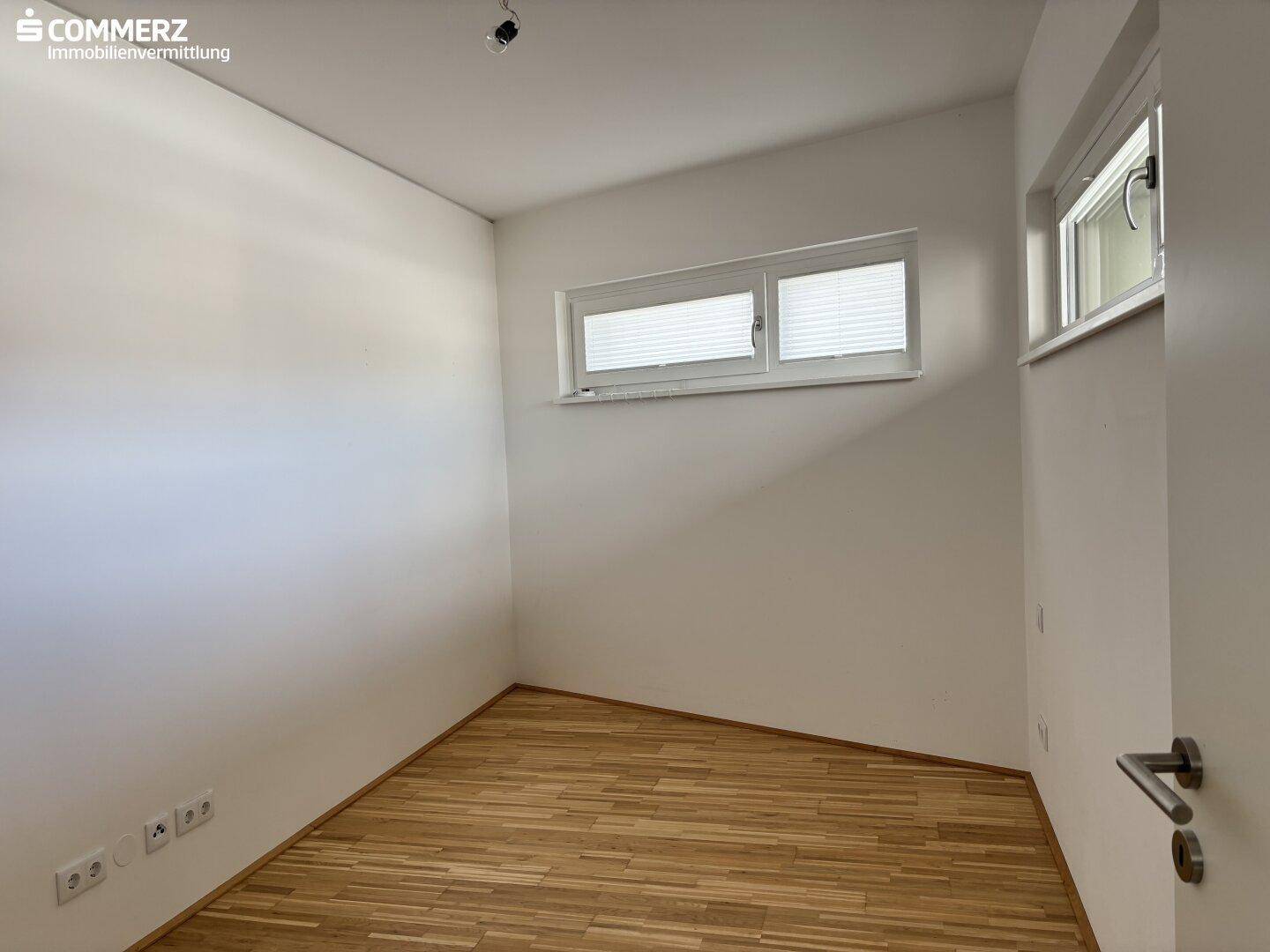Helles Schlafzimmer mit Parkettboden und Fenster, ideal für individuelle Einrichtungsideen.