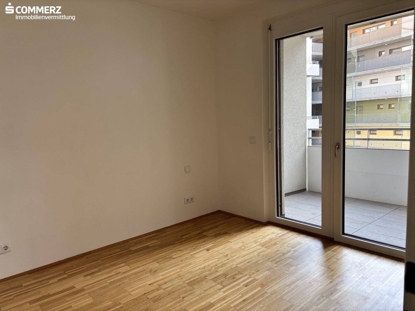Helles Zimmer mit Parkettboden und direktem Zugang zu einem Balkon, vielseitig nutzbar.