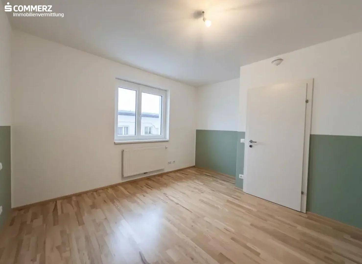 Schlafzimmer mit hellem Holzboden und zweifarbigen Wänden, bereit zur individuellen Gestaltung.