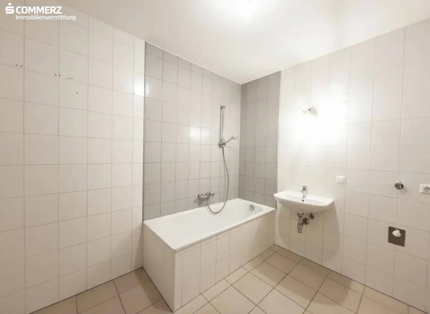 Badezimmer mit weißen Fliesen, Badewanne und Waschbecken, funktional und hell.