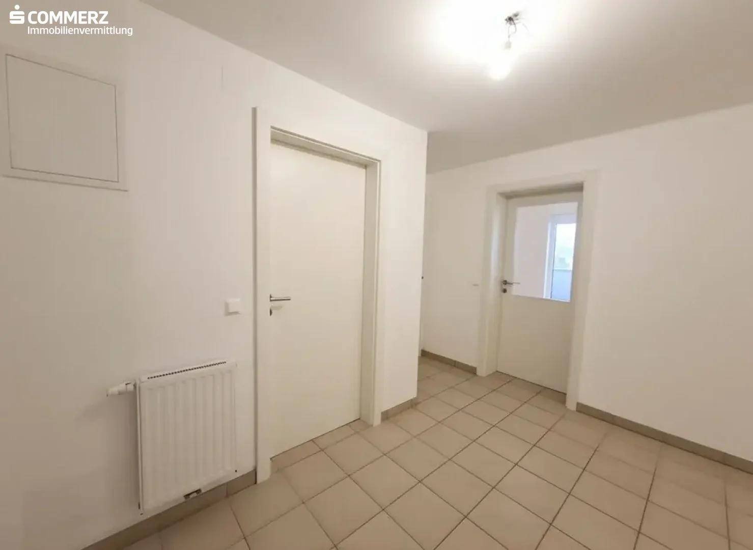 Heller Flur mit Fliesenboden und weißen Türen, verbindet die verschiedenen Räume.