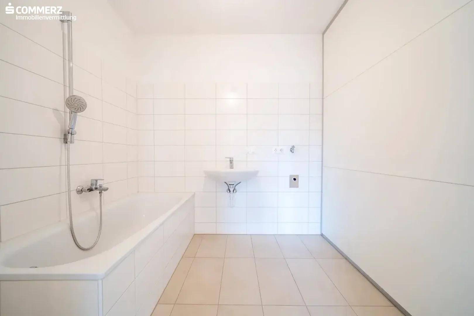 Modernes Badezimmer mit weißer Badewanne, Duscharmatur und hellem Fliesenboden.