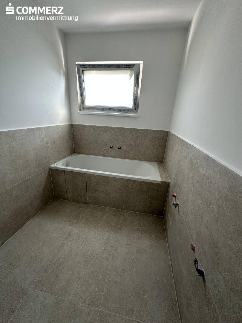 Modernes Badezimmer mit eingebauter Badewanne und hellen Fliesen, bereit für die Endmontage.