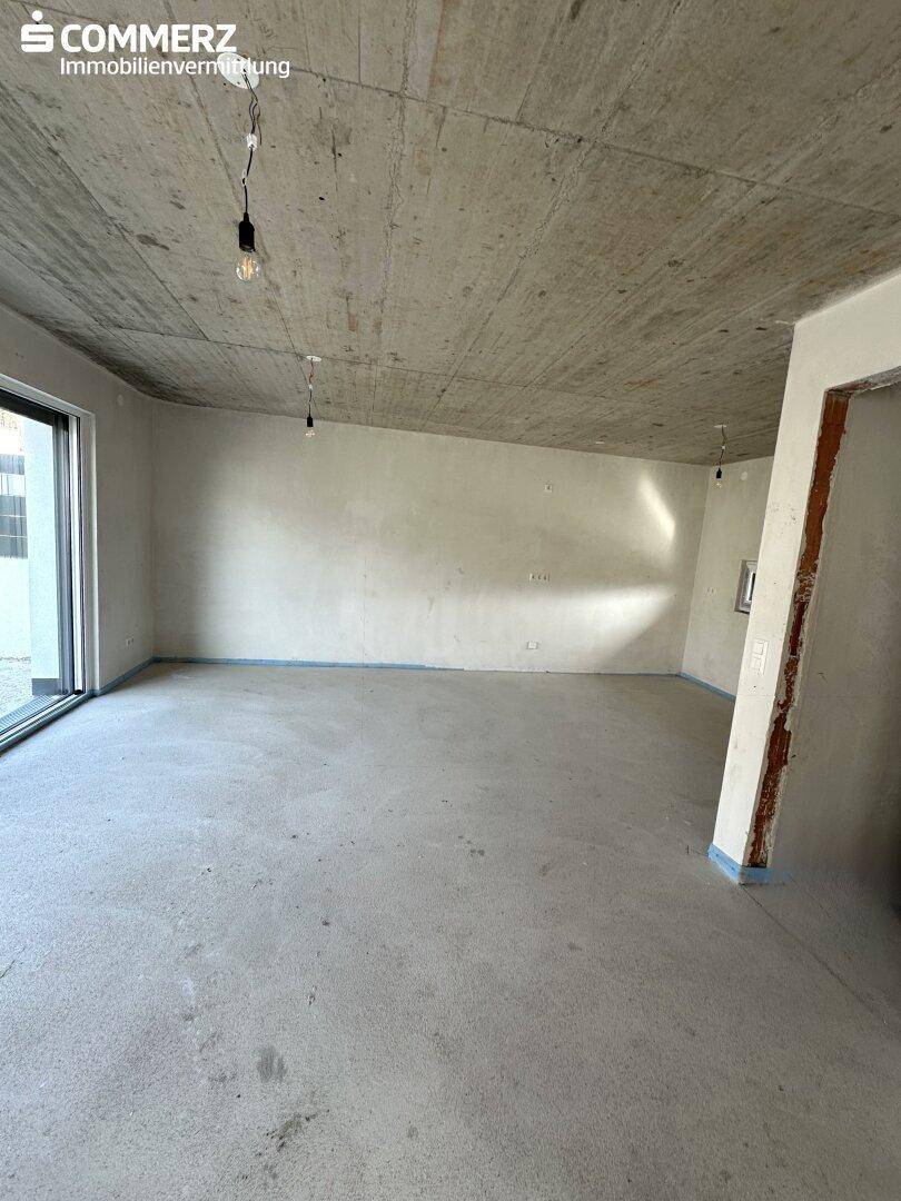 Rohbau-Innenraum mit unverputzten Wänden und Betonboden, bereit für den Ausbau.