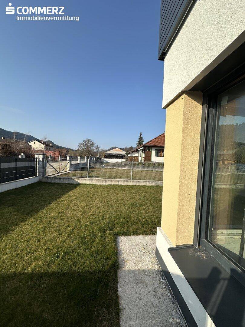 Grüne Rasenfläche neben einem modernen Haus mit Blick auf die Nachbarschaft und die Berge.