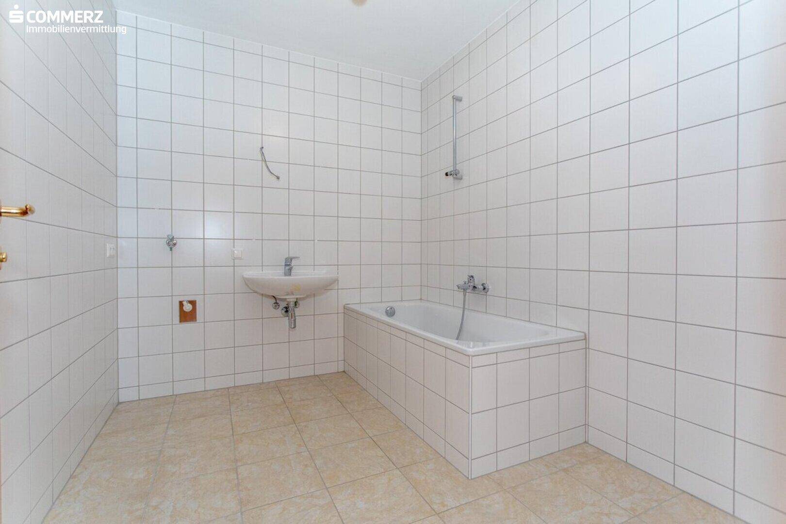 Gefliestes Badezimmer mit Badewanne und Waschbecken, bereit für die individuelle Gestaltung.