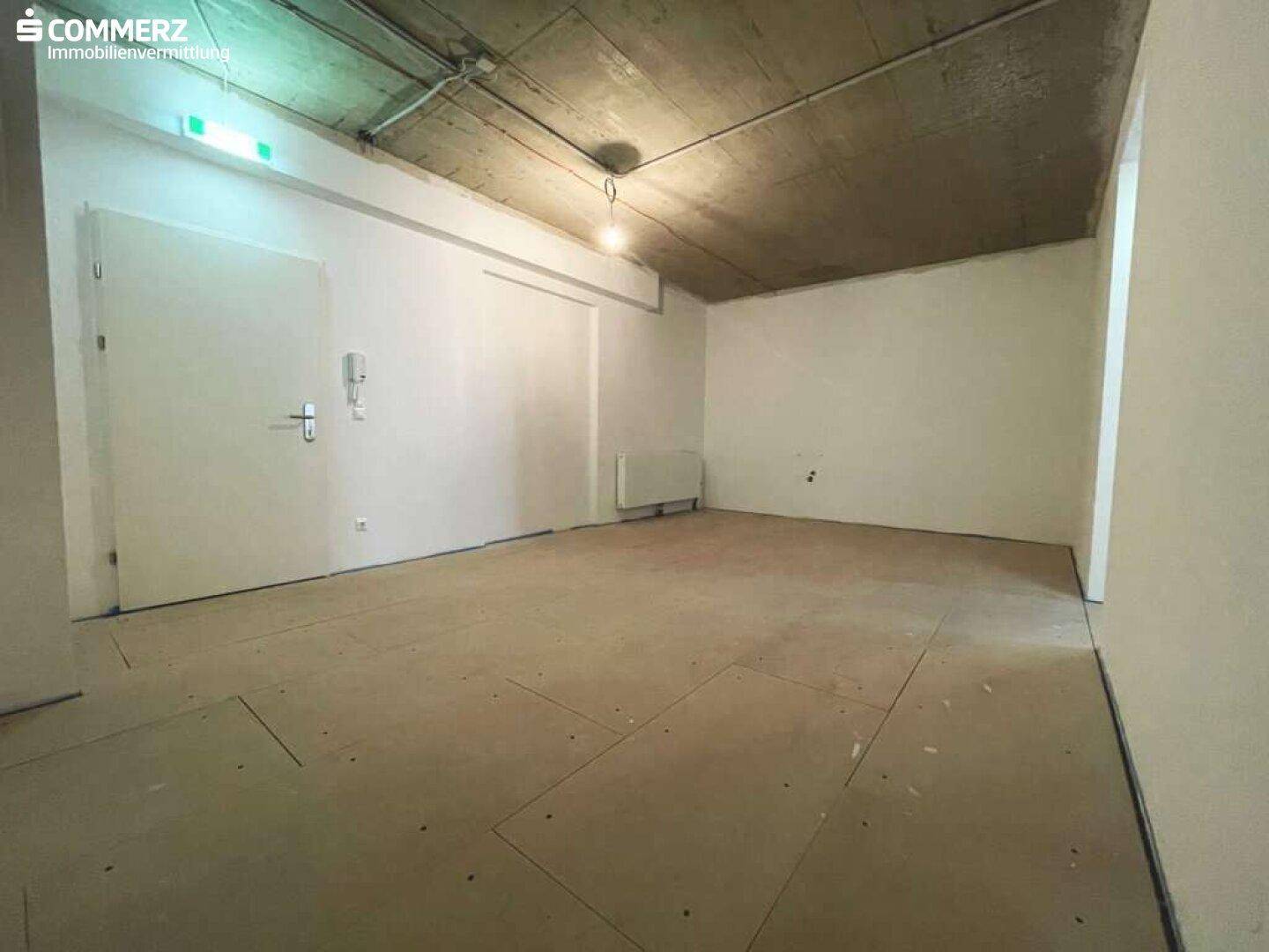 Kleinerer, unmöblierter Raum im Rohbauzustand mit Betonoptik an der Decke und einer Heizung an der Wand.