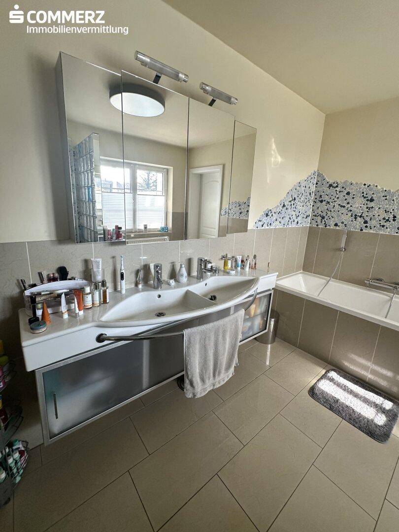 Helles Badezimmer mit Doppelwaschbecken, Badewanne und großem Spiegelschrank.