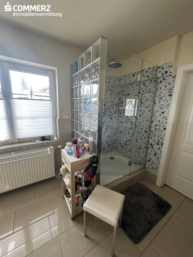 Badezimmer mit Duschkabine, Glasbausteinwand und Fenster für natürliches Licht.