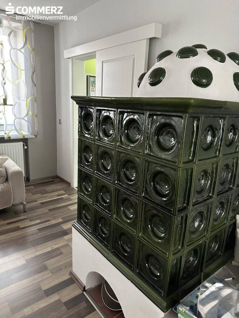 Gemütliches Wohnzimmer mit traditionellem Kachelofen und Laminatboden.