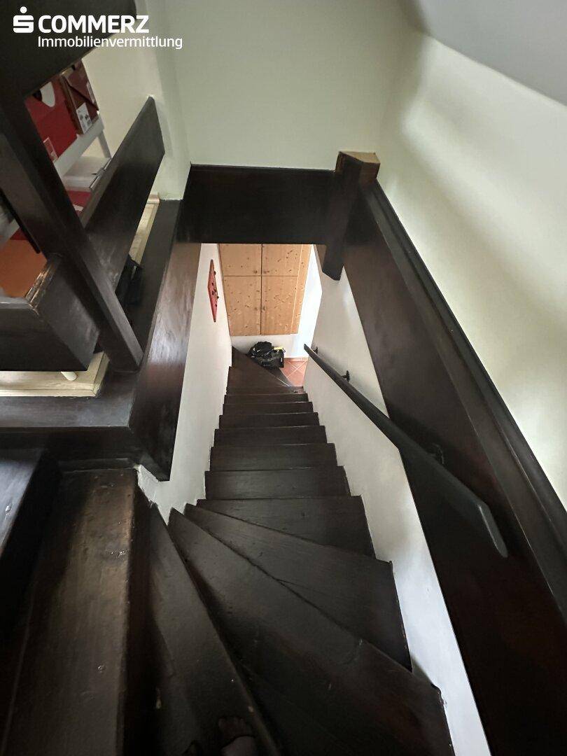 Dunkle Holztreppe führt in das obere Stockwerk mit sichtbarer Holzverkleidung.