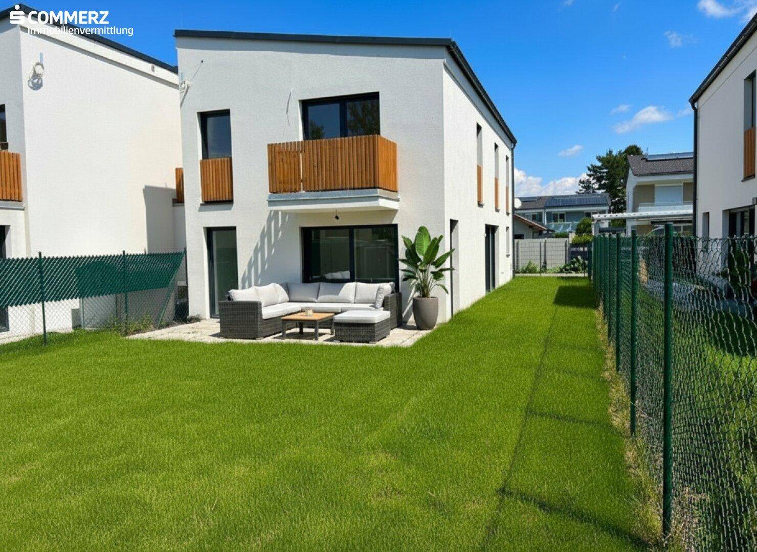 Moderne Doppelhaushälfte mit gepflegtem Rasen, Terrasse und Balkon in sonniger Lage.