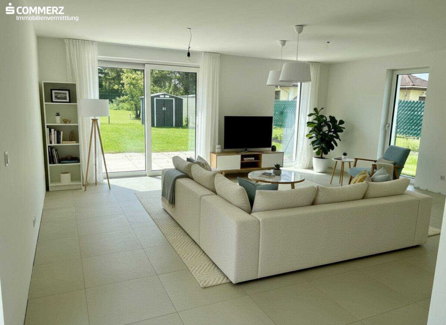 Helles Wohnzimmer mit großem Sofa, Fliesenboden und Zugang zum Gartenbereich.
