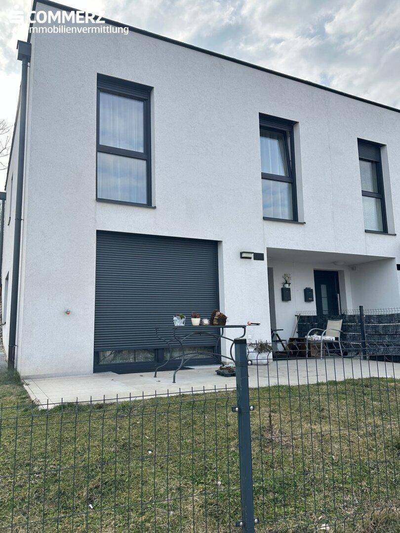 Vorderansicht eines modernen Reihenhauses mit kleiner Terrasse und Außenrollläden.