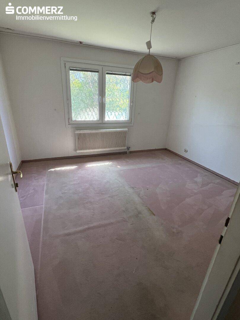 Schlafzimmer mit hellem Teppichboden, weißen Wänden und einem Fenster.