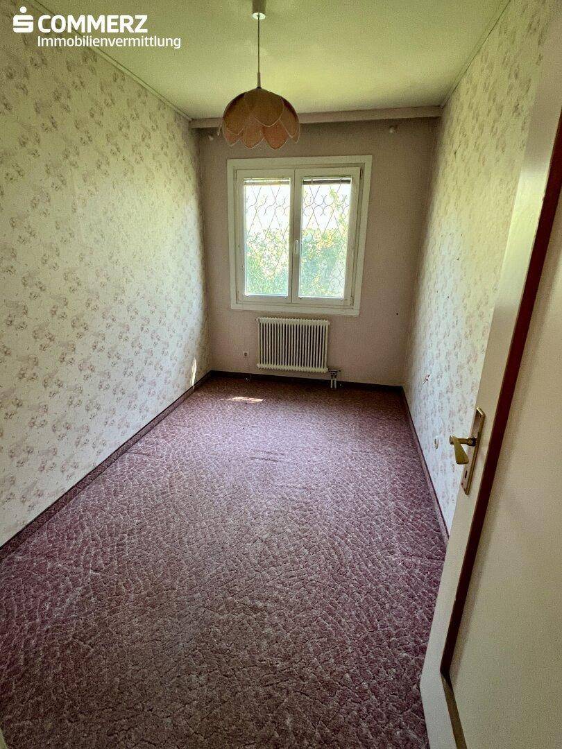 Schlafzimmer mit Teppichboden, gemusterter Tapete und einem Fenster.