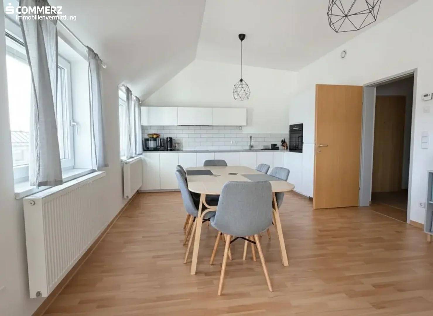 Moderne Einbauküche mit Essbereich und Dachschräge, ausgestattet mit zeitgemäßen Geräten.