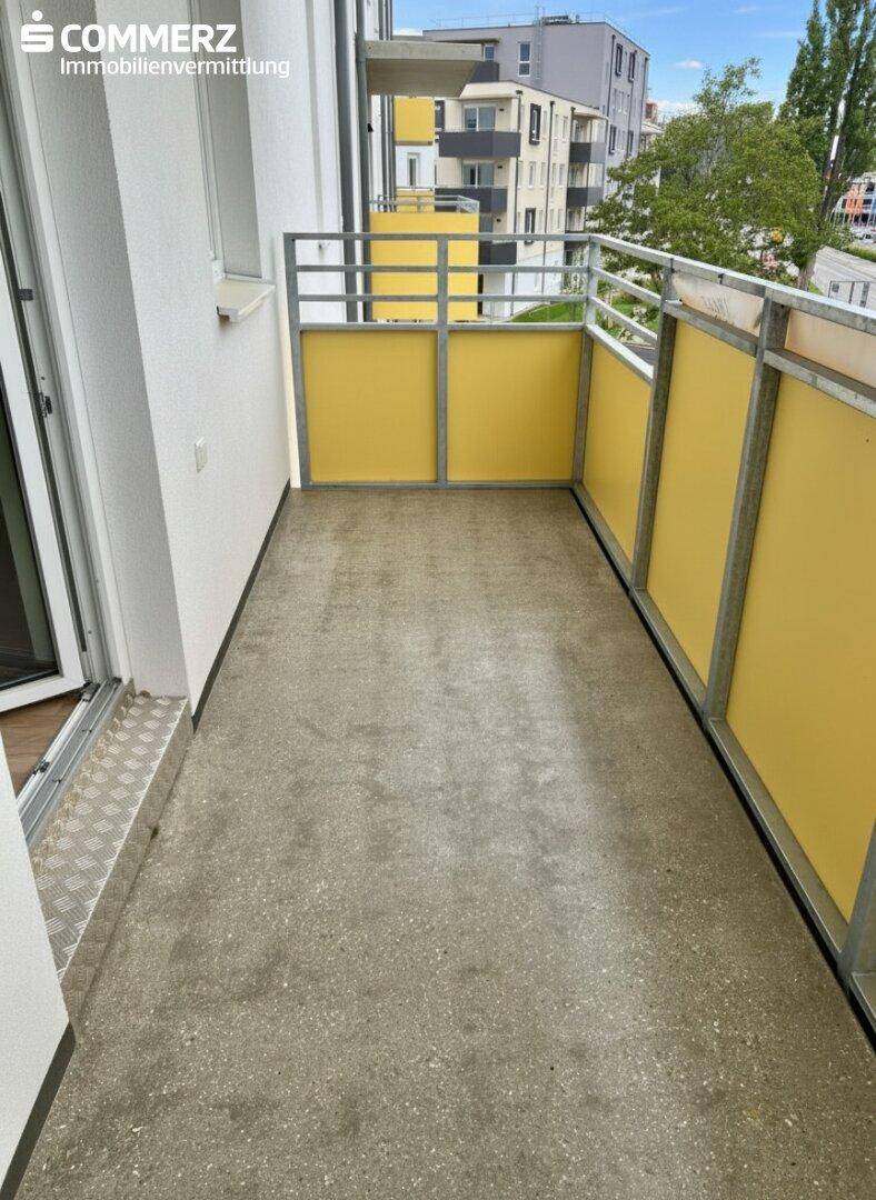 Leerer Balkon mit Betonboden und gelben Sichtschutzelementen, bereit zur individuellen Gestaltung.